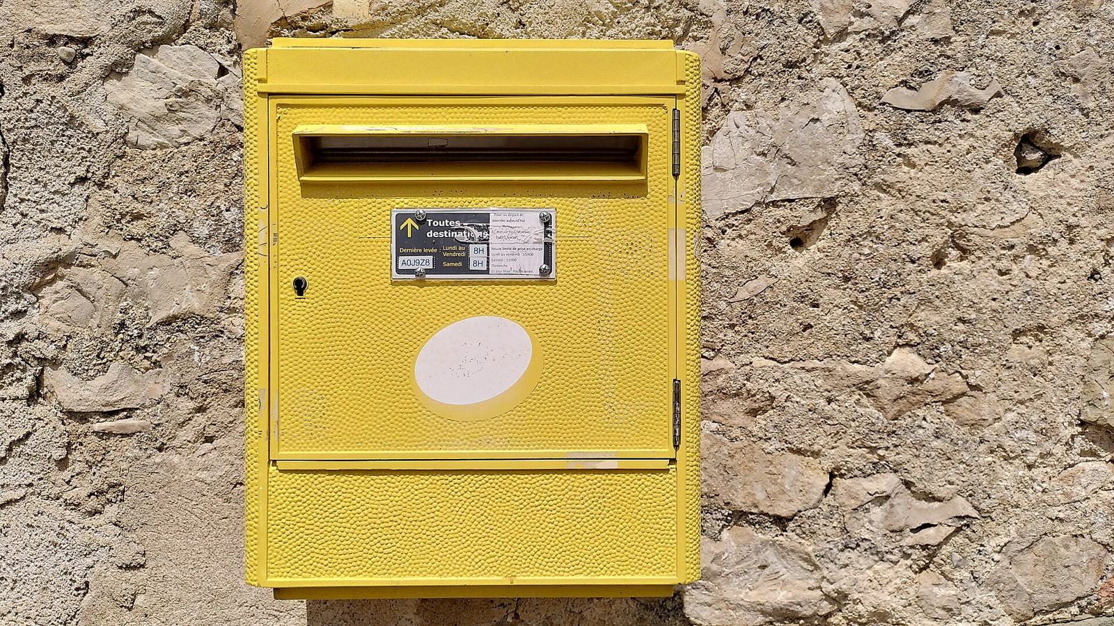 Boîte aux lettres jaune fixée à un mur